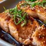 Delicious baked teriyaki salmon garnished with sesame seeds and scallions.