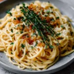 Plate of creamy French onion pasta garnished with herbs