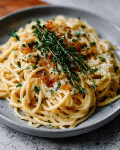 Plate of creamy French onion pasta garnished with herbs