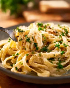 Creamy Crockpot Chicken Alfredo served with pasta and herbs