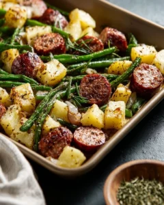 Sheet pan meal featuring sausage, potatoes, and green beans roasted together.