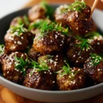 Bowl of delicious Saucy Asian Meatballs garnished with sesame seeds and green onions