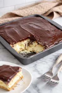 No Bake Chocolate Eclair Cake topped with chocolate glaze and whipped cream