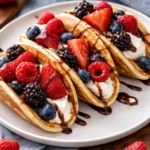 Plate of delicious pancake tacos filled with fruits and syrup