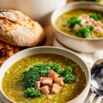 Bowl of split pea and ham soup garnished with herbs