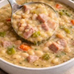 A bowl of delicious Ham and Bean Soup garnished with herbs and served with bread.