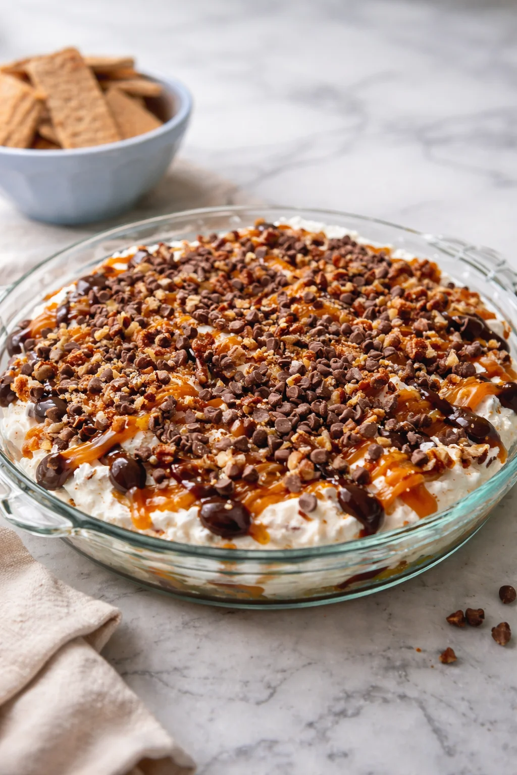 Delicious turtle cheesecake dip served with graham crackers and chocolate drizzle.