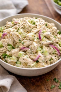 A bowl of fresh chicken salad with colorful vegetables and dressing