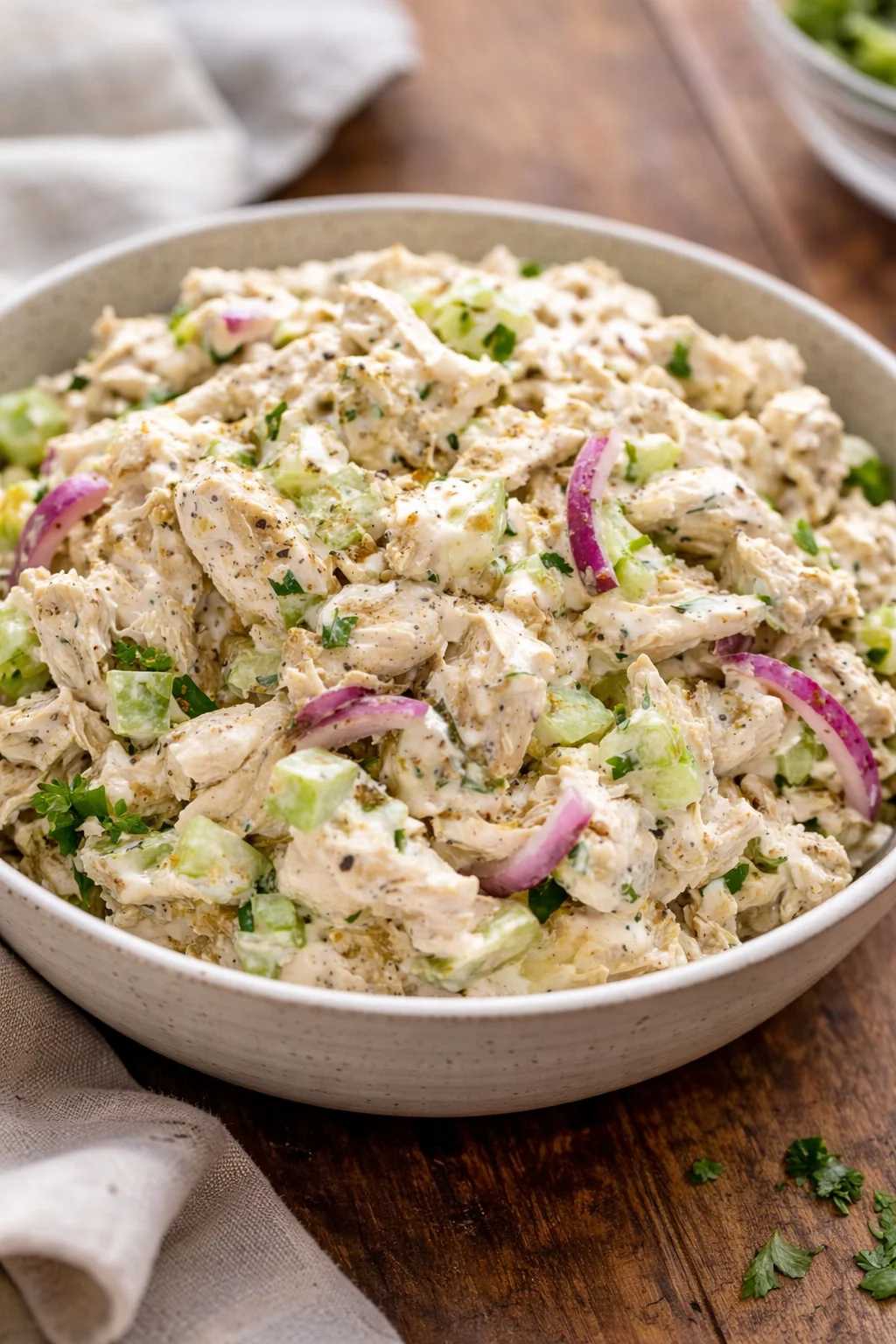 A bowl of fresh chicken salad with colorful vegetables and dressing
