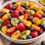 Colorful fresh fruit salad with honey lime poppy seed dressing on a white plate