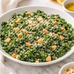 Bowl of Lemon Parm Kale Salad topped with grated Parmesan cheese and lemon slices