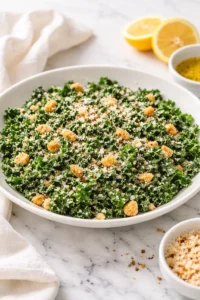 Bowl of Lemon Parm Kale Salad topped with grated Parmesan cheese and lemon slices
