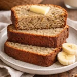 A slice of moist banana bread on a rustic wooden table