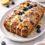 Freshly baked sourdough blueberry lemon bread sliced on a wooden board.