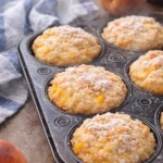 Delicious peach cobbler muffins fresh out of the oven with juicy peach filling