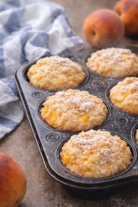 Delicious peach cobbler muffins fresh out of the oven with juicy peach filling