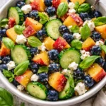 Blueberry Peach Feta Salad drizzled with lemon dressing on a white plate