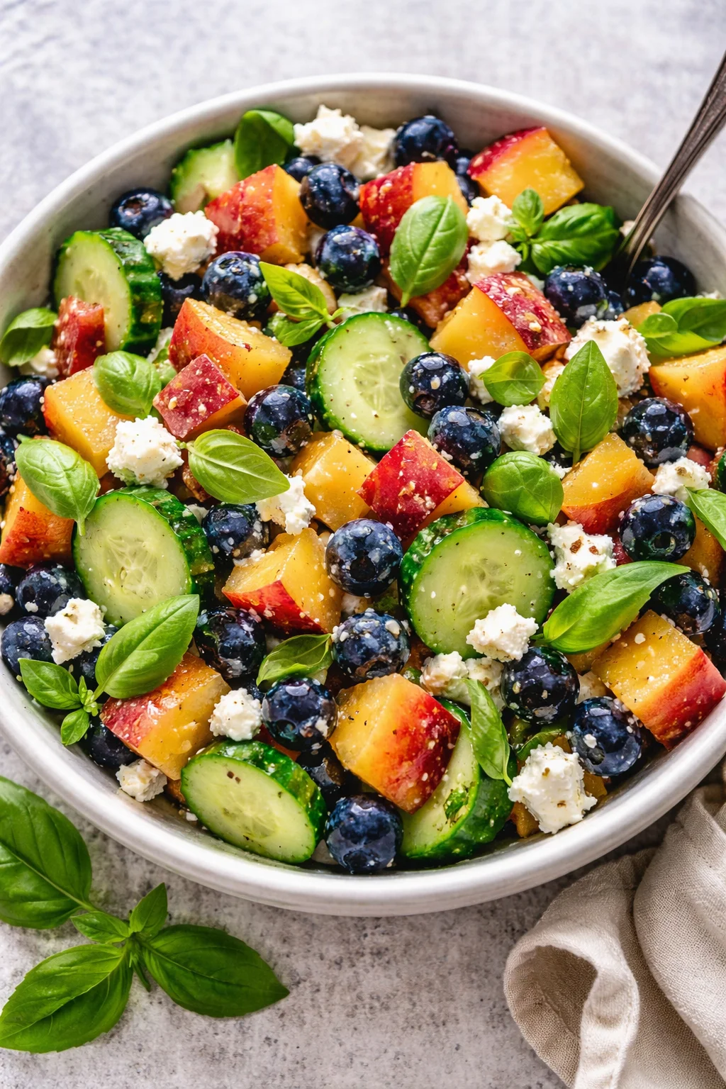 Blueberry Peach Feta Salad drizzled with lemon dressing on a white plate