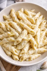 Creamy garlic penne pasta garnished with herbs and parmesan cheese