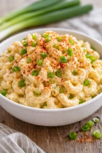 A bowl of colorful Deviled Egg Pasta Salad with eggs, pasta, and herbs
